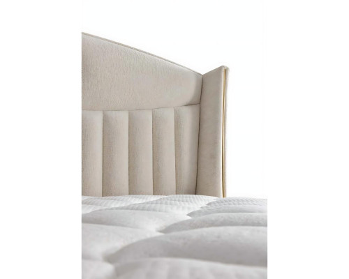 Säng elegant med kuddar i ljusgrått tyg och trä